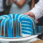 Nothing Bundt Cake being sliced to reveal blue frosting, surrounded by clapping guests.